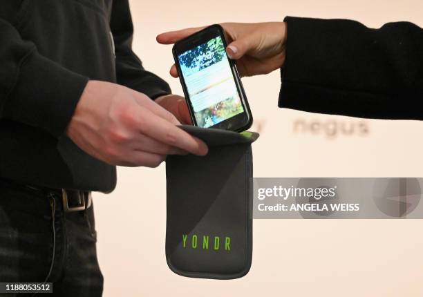 Mobile phones are locked into 'Yondr' pouches before people enter an exhibition at the Brooklyn Museum on November 22, 2019 in New York City. Yondr...