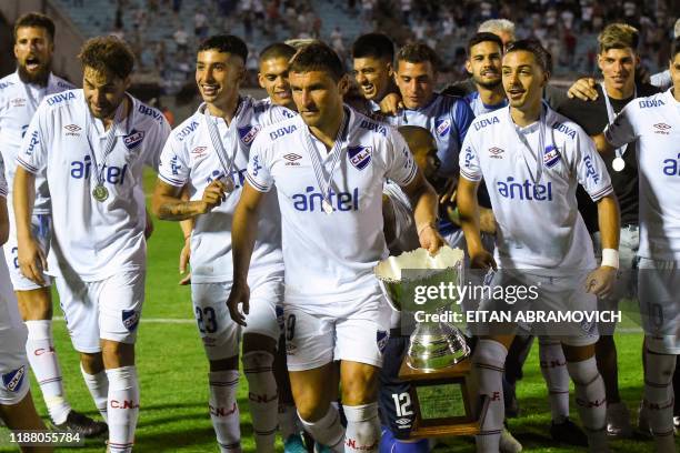 Nacional's captain Gonzalo Bergessio carries the trophy followed by Nacional's player after obtaining the Uruguayan Clausura football tournament by...