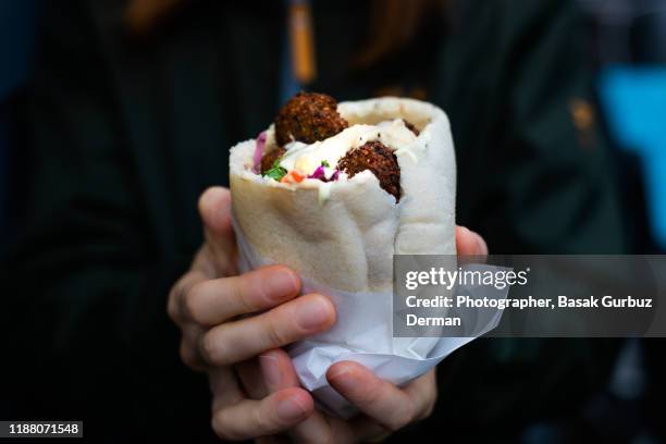 a woman's hands holding felafels in pita bread - pitta bread stock pictures, royalty-free photos & images