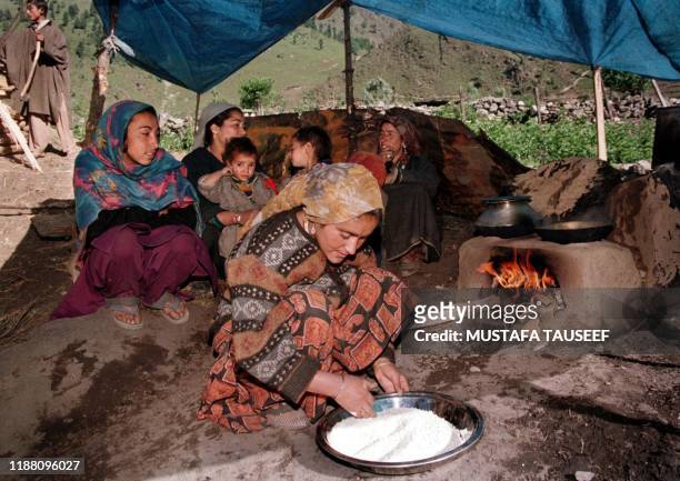 Refugees from the Dras sector prepare rice under a tent in a makeshift refugee camp about 70 kilometres north-east of Srinagar, 15 June 1999....