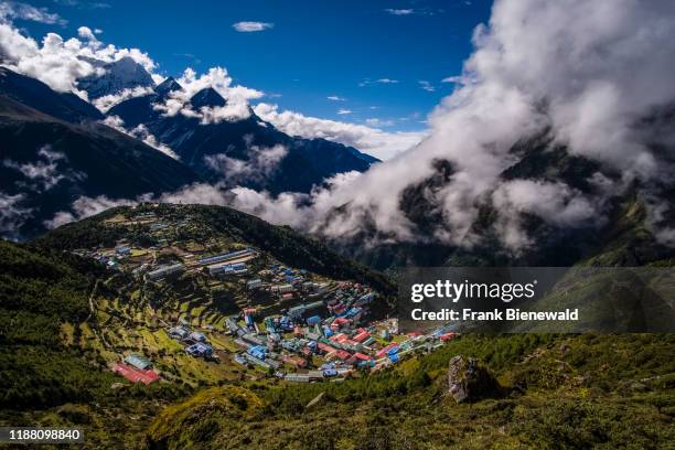Panoramic aerial view over the town, mountainous landscape and snow-covered peak of Mt. Thamserku in the distance.