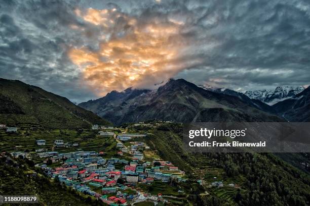 Panoramic aerial view over the town at sunrise, mountainous landscape covered in monsoon clouds in the distance.