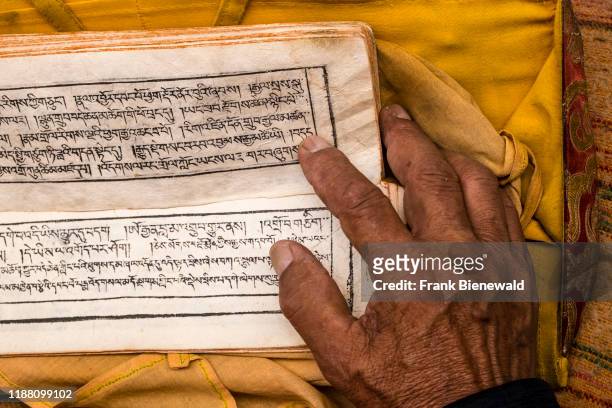 Hand of a monk turning pages of a tibetan prayer book.