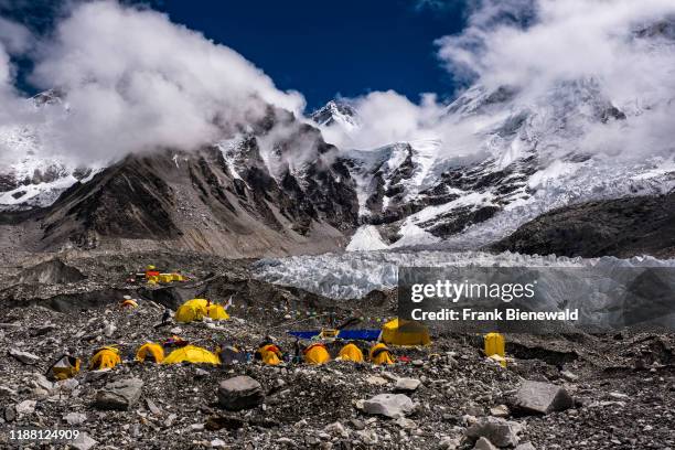 Tents set up at Everest Base Camp on Khumbu glacier, Mt. Everest behind covered by monsoon clouds.