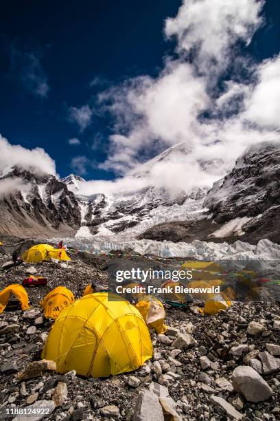 Tents set up at Everest Base Camp on Khumbu glacier, Mt. Everest behind covered by monsoon clouds.