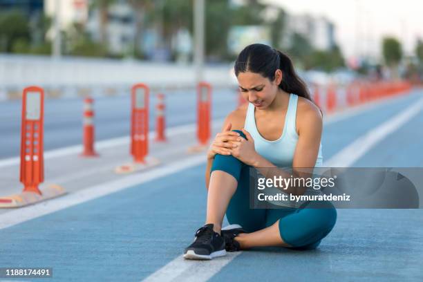 läuferin klammert sich an verletztes knie - female knee pain stock-fotos und bilder