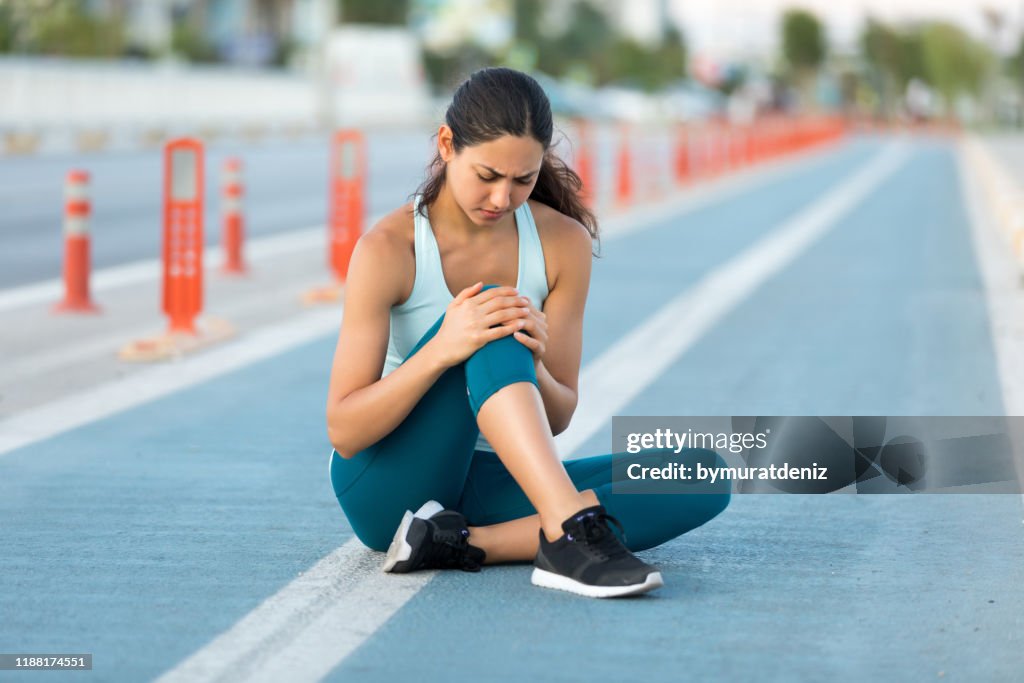 Female runner clutching injured knee