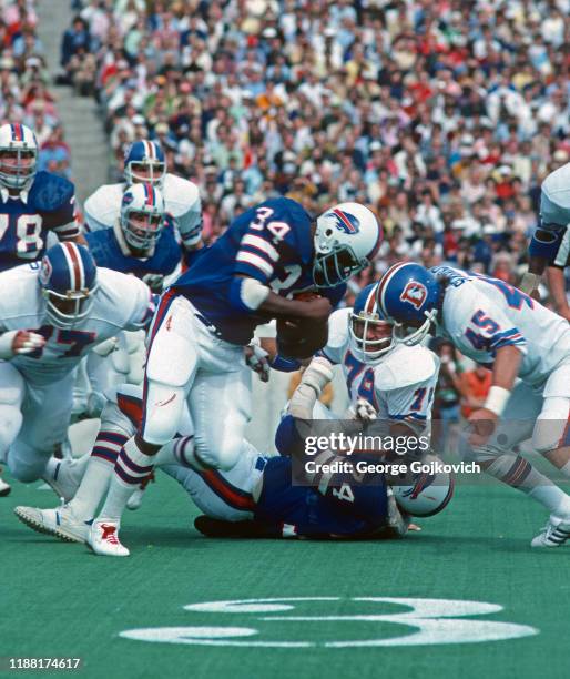 Running back Jim Braxton of the Buffalo Bills runs against safety Jeff Severson and defensive linemen Lyle Alzado and Barney Chavous of the Denver...