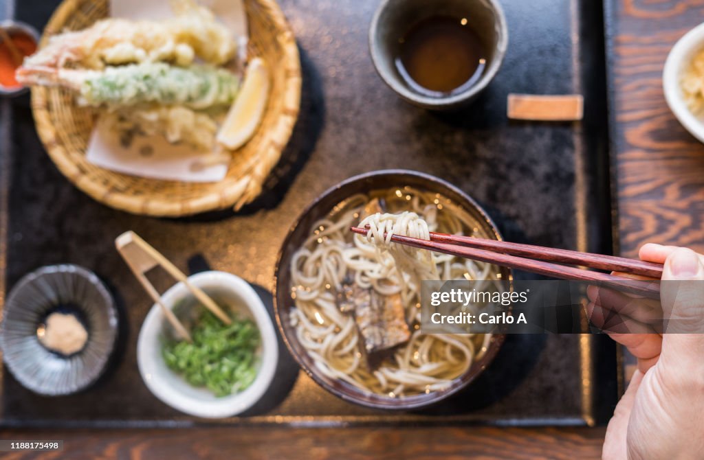 Overhead first person view of hands eating ramen soup