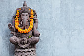 Ganesha sitting in meditating yoga pose in hindu temple.