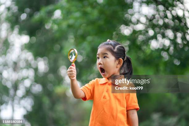 mädchen verwendet lupe, um freude zu finden - child magnifying glass stock-fotos und bilder