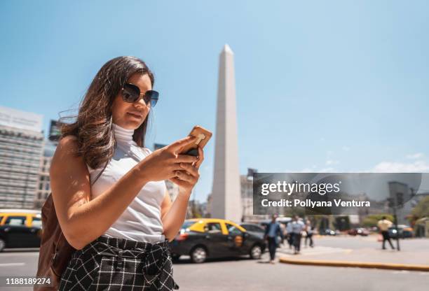 femme utilisant le téléphone portable devant obelisco de buenos aires - buenos aires photos et images de collection