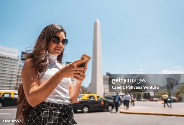 オベリスコ・デ・ブエノスアイレスの前で携帯電話を使う女性 - argentinian ストックフォトと画像