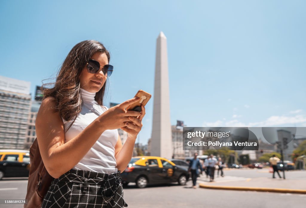 Vrouw die mobiele telefoon gebruikt voor Obelisco de Buenos Aires