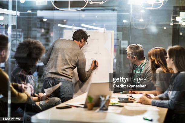 mittlere erwachsene geschäftsmann schreiben pläne während der präsentation mit seinen kollegen im büro. - business strategy stock-fotos und bilder