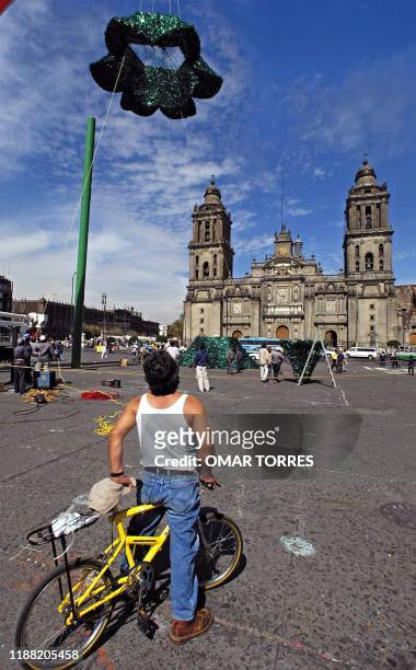 Cyclist watches workers as build a Christmas tree in Mexico City 13 December 2001. Uno hombre observa desde su bicicleta a trabajadores de la...