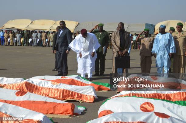 Mahamadou Issoufou , the President of Niger, bows in front of the bodies of military personnel at the Niamey Airforce Base in Niamey, on December 13,...