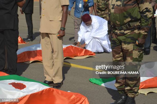 Mahamadou Issoufou , the President of Niger, bows in front of the bodies of military personnel at the Niamey Airforce Base in Niamey, on December 13,...