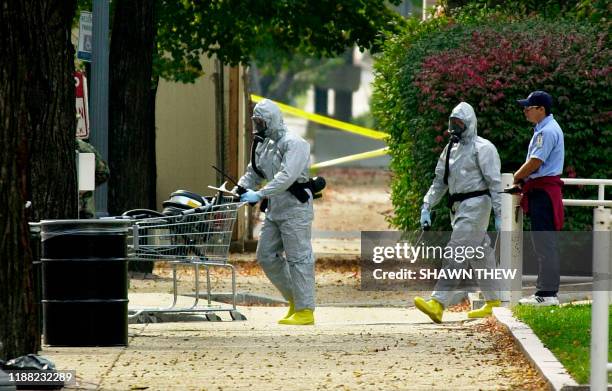 Workmen in biohazard suits push a cart of equipment 23 October 2001 into the Longworth House Office building on Capitol Hill in Washington, DC after...