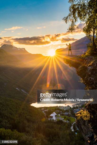 tourist photographing geiranger with smartphone from top of cliff, norway - westelijke fjorden noorwegen stockfoto's en -beelden