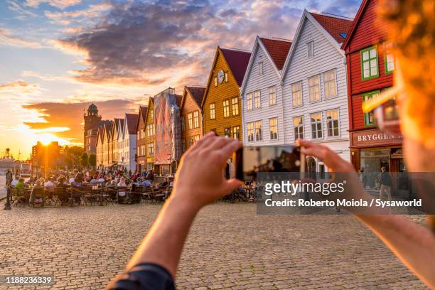 tourist photographing bryggen houses with smartphone, bergen, norway - bergen stock pictures, royalty-free photos & images