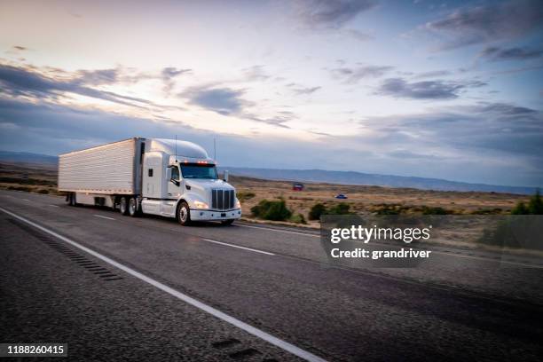 long haul semi trucks speeding down a four lane highway to delivery their loads - highway blue sky car stock-fotos und bilder