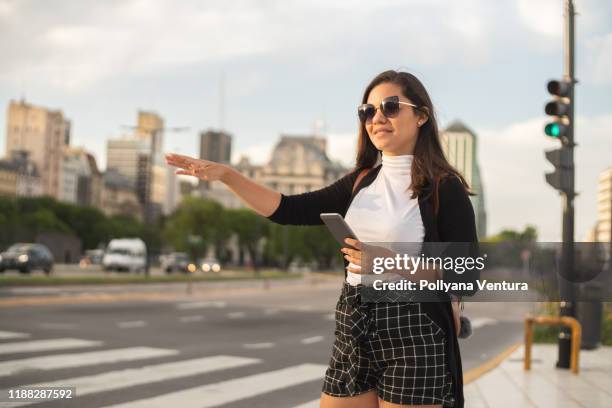 woman hailing taxi from her mobile app in buenos aires - uber in buenos aires argentina stock pictures, royalty-free photos & images