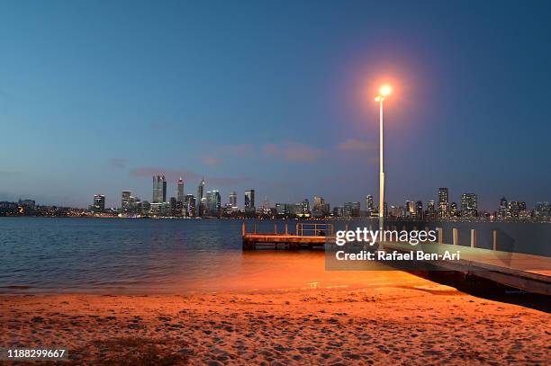 perth central business district skyline as view from the swan river bank pier at dusk - perth cbd stock pictures, royalty-free photos & images