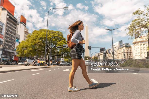 woman crossing the traffic signal in buenos aires - obelisco de buenos aires stock pictures, royalty-free photos & images
