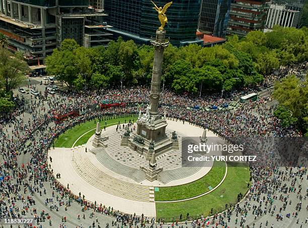 Bus carrying Mexico's Under-17 national football team is followed by cheering supporters as they ride around Mexico City's Independence Monument, on...