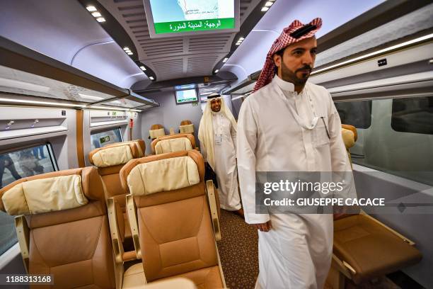 Men walk through a carriage of a Haramain High Speed train, part of a network linking Saudi Arabia's two Muslim holy cities of Mecca and Medina,...