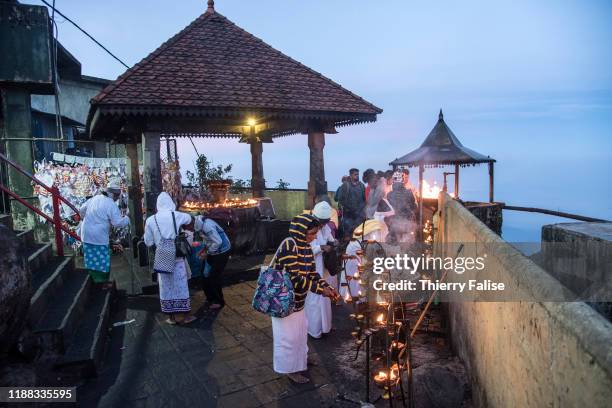 Buddhist pilgrims light candles with blessed oil while waiting for the sunrise at the top of Adam's Peak. Adam's Peak is a 2,243 meter conical...