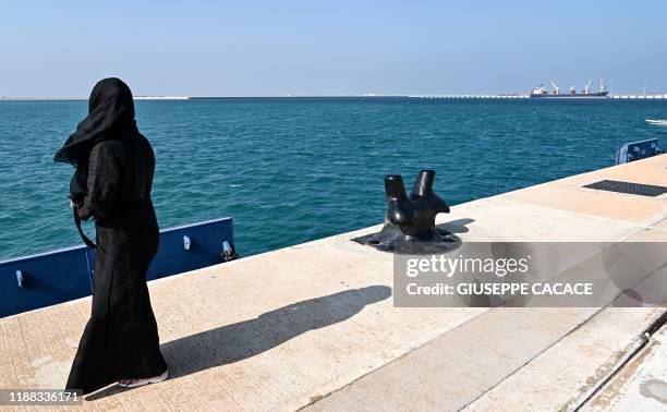 Woman looks on as she stands along a pier at the docks of Ras al-Khair port, about 185 kilometres north of Dammam in Saudi Arabia's eastern province...