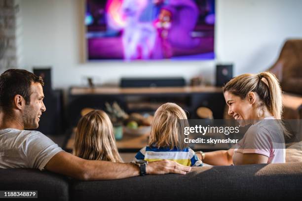 vista traseira de uma família que presta atenção à tevê no sofá em casa. - family watching tv - fotografias e filmes do acervo