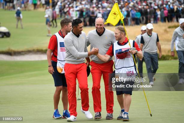 Teams Tony Finau and caddie John Wood shake hands with U.S. Teams Matt Kuchar during the third round of four-ball matches at the Presidents Cup at...