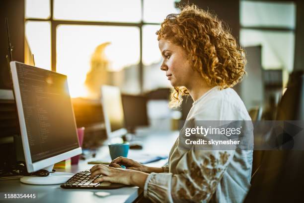 redhead vrouwelijke programmeur coderen computer software op kantoor. - woman coding stockfoto's en -beelden
