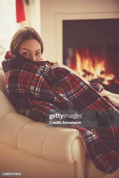 young woman relaxing next to a fireplace - cosy blanket stock pictures, royalty-free photos & images