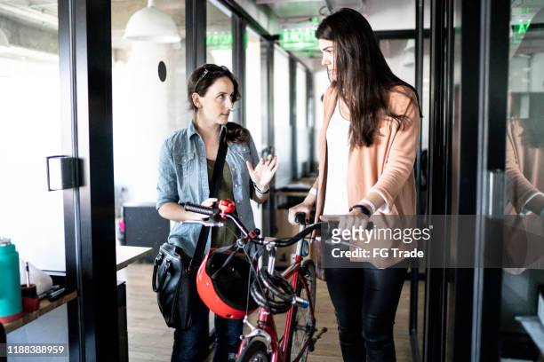 Coworkers walking with bicycle at office corridor