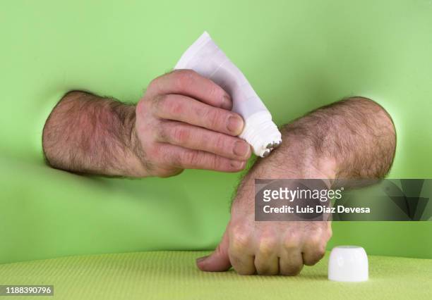 man applying cream with plastic massage tube with 3 roller ball applicator - hand on knee stock photos et images de collection