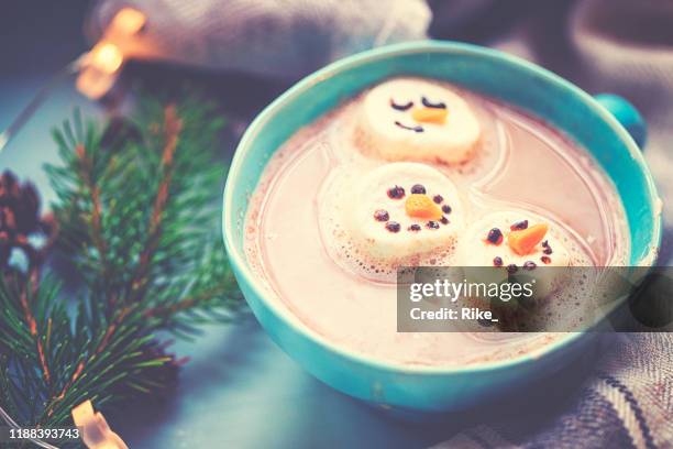 kerst bereidingen van een marshmallow sneeuwpop voor de warme chocolademelk - marshmallow stockfoto's en -beelden