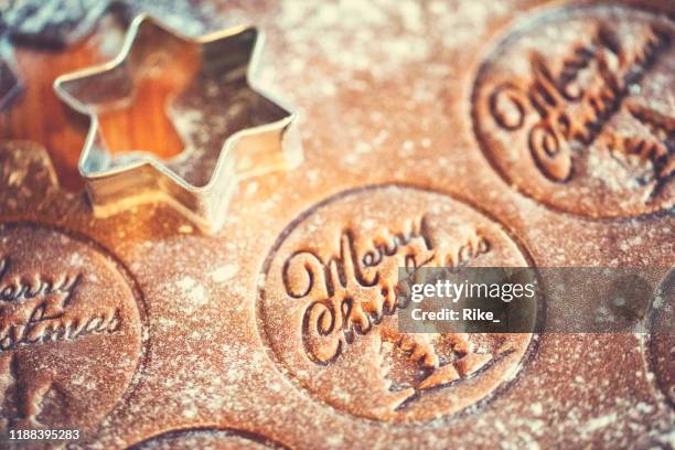 ausschneiden von weihnachtsplätzchen mit schriftzug frohe weihnachten - shortbread stock-fotos und bilder