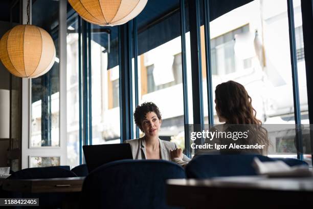 two women with computer in meeting at a cafe - business meeting cafe stock pictures, royalty-free photos & images