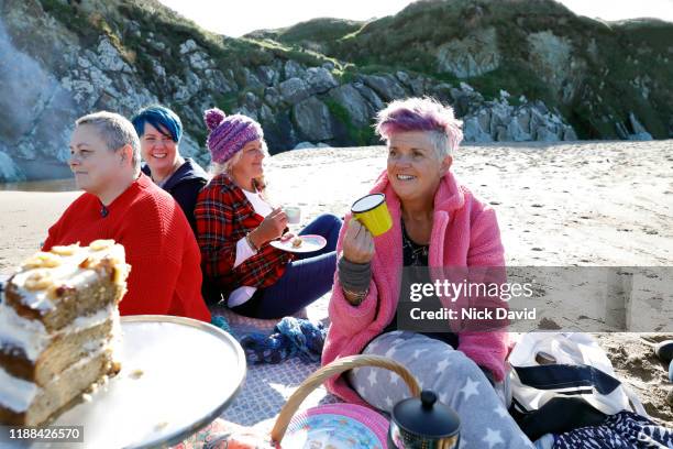 a group of women friends laughing and celebrating together on a sunny day at the beach. - only mature women stockfoto's en -beelden