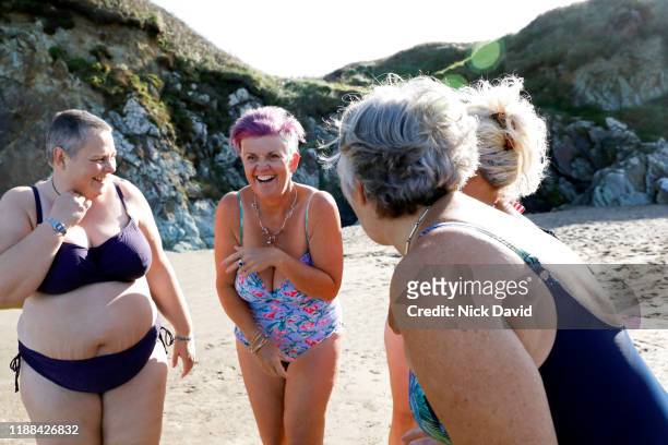 A group of women laughing and having fun together as they get ready for a swim in the sea.