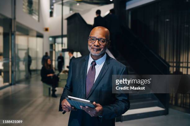 portrait of entrepreneur in formal wear while standing with digital tablet in office - formal office stock pictures, royalty-free photos & images
