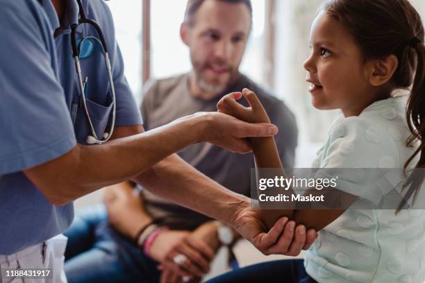 midsection of nurse examining girl sitting with father at clinic - girl medical exam stock pictures, royalty-free photos & images