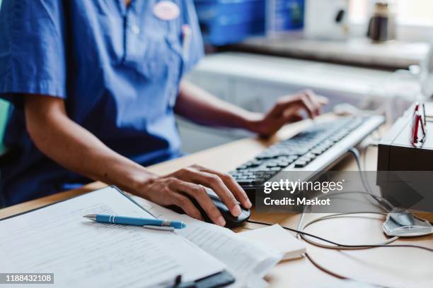 midsection of nurse using computer at desk in hospital - krankenakte stock-fotos und bilder