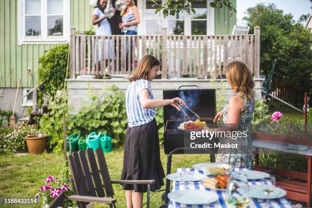 mother and daughter preparing food on barbecue in backyard party - backyard grilling stock pictures, royalty-free photos & images