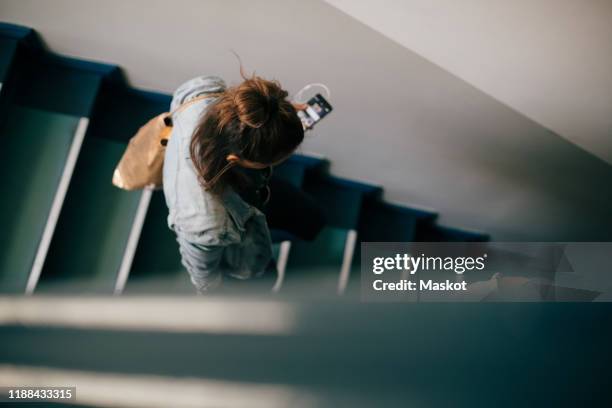 high angle view of woman moving down on stairs in apartment - staircase photos et images de collection