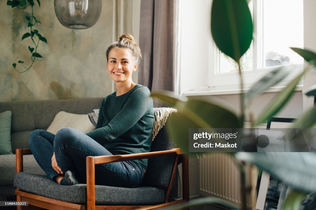 Portrait of smiling woman sitting on armchair at home